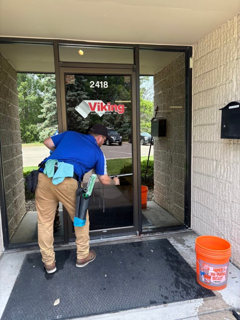 man in blue shirt in front of a business cleaning the glass door