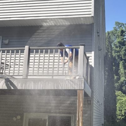 man on high deck using a power sprayer of sorts to clean the deck boards