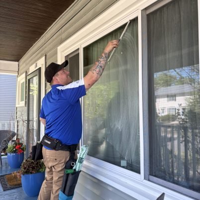 man wearing blue shirt cleaning exterior window in st paul mn