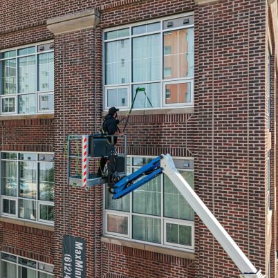 man in high ariel lift cleaning windows of a three story building