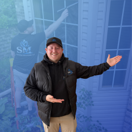 man in black jacket, holding out left arm as he is pointing to something, the background is overlayed blue, man washing a window